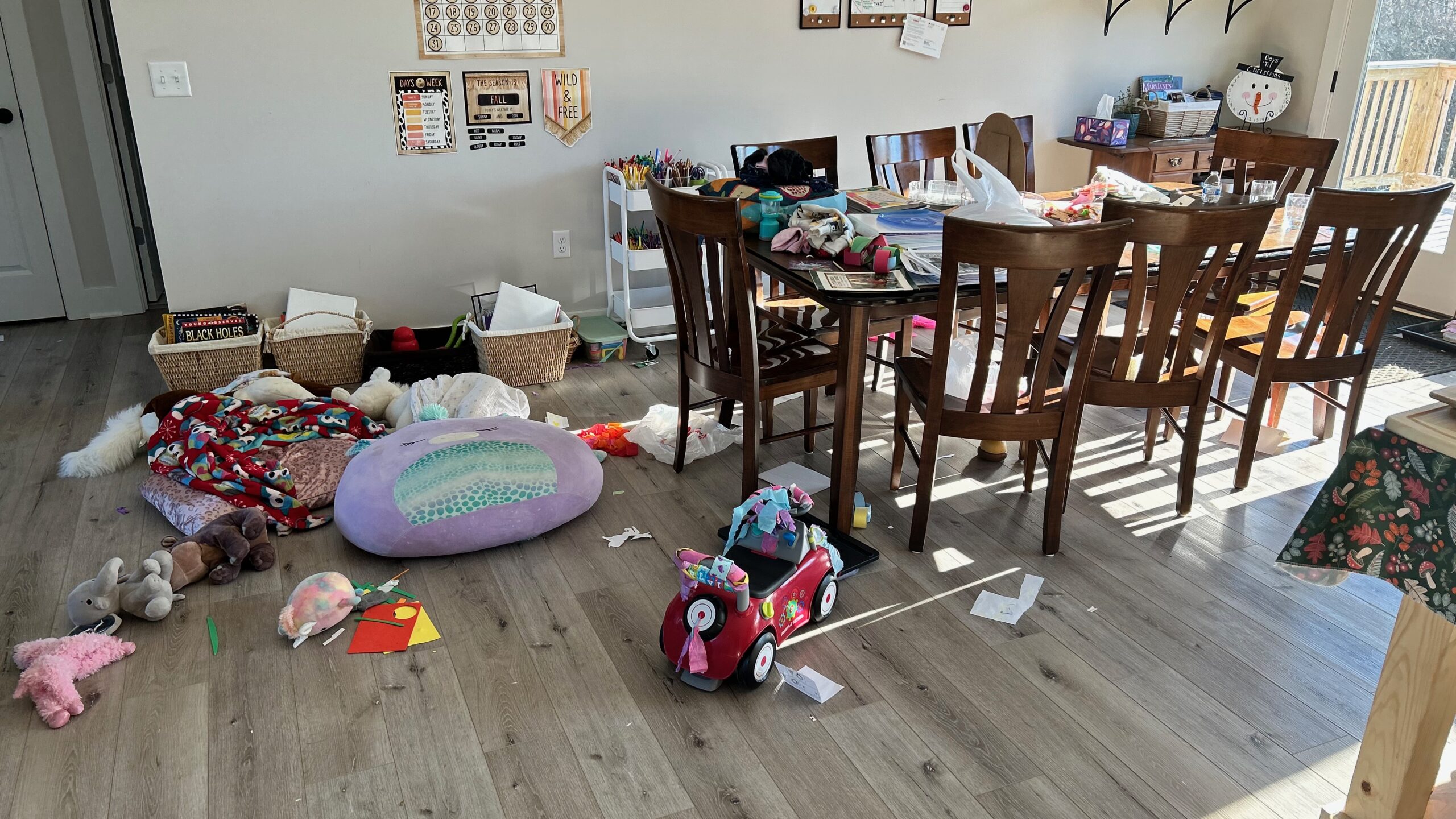 dining room table with clutter coving the surface. Floor covered with toys and clutter.